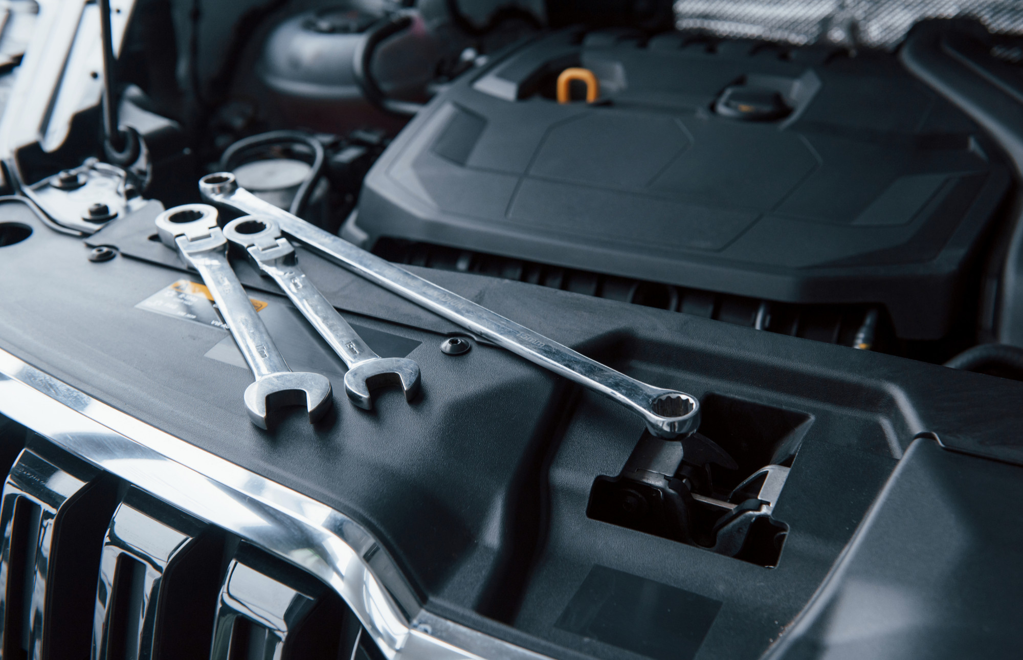 Three wrenches laid across the car hood over the engine bay, as if for a quick repair.